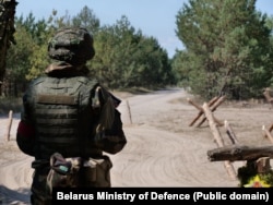 Беларускі вайсковец каля загародаў, зробленых зь бярвёнаў, на мяжы з Украінай. 22 жніўня 2024 году