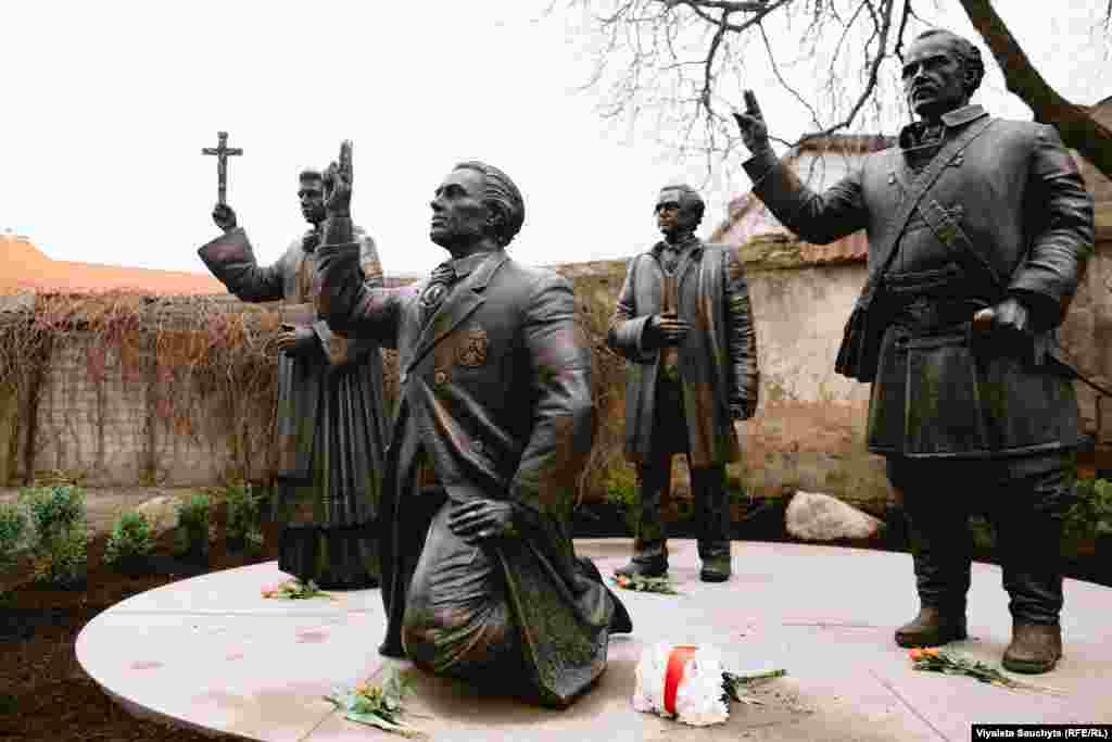 На пярэднім пляне ўкленчаны Каліноўскі, а за ягонай сьпінай &mdash; Серакоўскі, абодва з паднятымі ў жэсьце клятвы рукамі: прысягаюць у вернасьці Богу і Радзіме. Воддаль стаіць скульптура Далеўскага