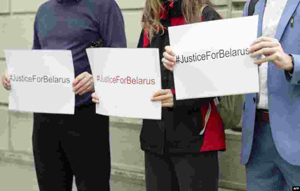 Плякаты з аднолькавым надпісам Justice for Belarus (Справядлівасьць для Беларусі) у руках праваабаронцаў перад слуханьнямі ў крымінальнай справе ва ўнівэрсальнай юрысдыкцыі.