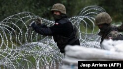 Польскія вайскоўцы ўзводзяць загароду з калючага дроту на мяжы зь Беларусьсю, жнівень 2021 г.