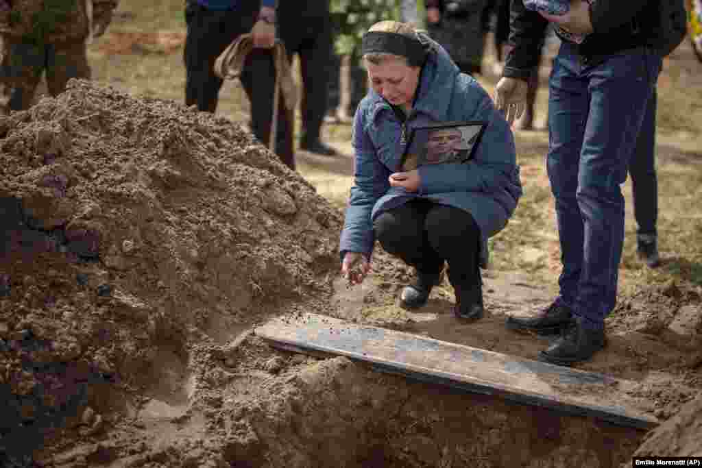 Ірына Тромса кідае зямлю ў магілу свайго сына, 24-гадовага Багдана. Буча, 23 красавіка 2022. Багдан быў украінскім дэсантнікам, які загінуў у баях з расейскімі войскамі на паўночным усходзе сваёй краіны.