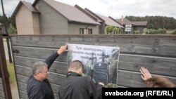 Актывісты вывешваюць плякаты на агароджы забаўляльнага комплексу, у якім адкрылася рэстарацыя, 7 чэрвеня 2018